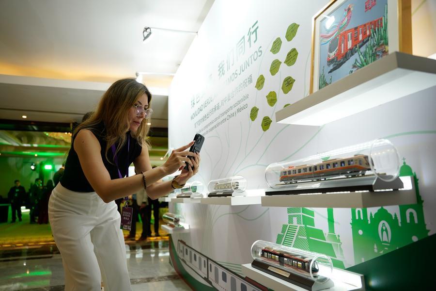 Imagen cedida por CRRC Corporation Limited del 2 de julio de 2026 de una mujer tomando una fotografía de la maqueta de un tren durante el evento "Futuro Verde: Movilidad Sostenible y Aprendizaje Mutuo entre Civilizaciones", en la Ciudad de México, capital de México. (Xinhua/CRRC Corporation Limited) 