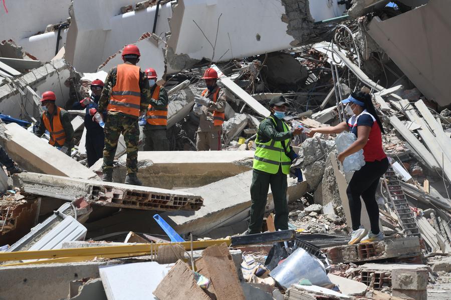 Una voluntaria proporciona agua a integrantes de la Fuerza Armada Nacional Bolivariana durante tareas de remoción de escombros en un edificio colapsado luego de que se registraran dos terremotos, en Caraballeda, estado La Guaira, Venezuela, el 7 de julio de 2026. (Xinhua/Marcos Salgado)
