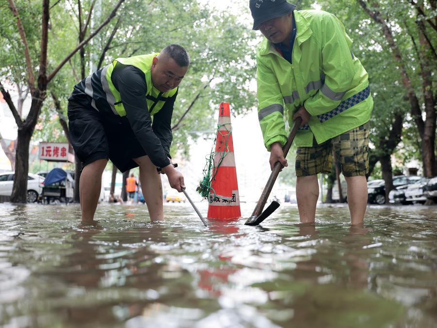 Operarios del servicio de drenaje municipal trabajan en una carretera inundada en el distrito de Tiexi, ciudad de Shenyang, provincia de Liaoning, en el noreste de China, el 14 de julio de 2026. (Xinhua/Li Gang). 