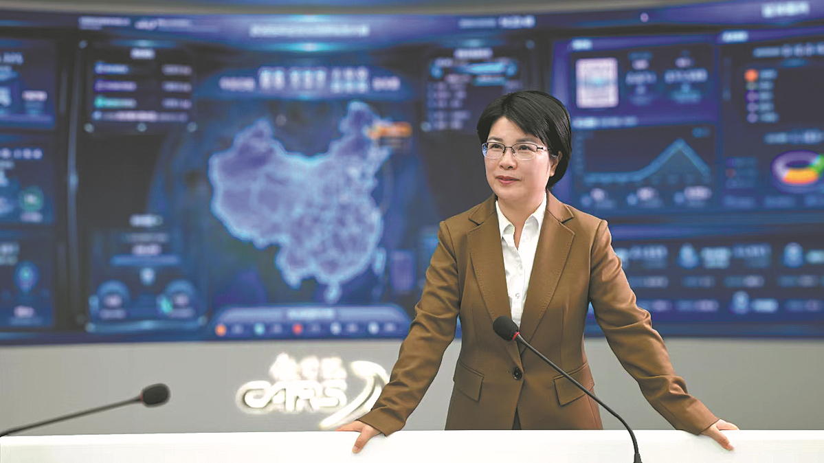 Shan Xinghua posa ante unas pantallas donde se muestra el sistema de venta de billetes ferroviarios 12306 de China, plataforma que ella contribuyó a desarrollar hasta convertirla en uno de los sistemas de venta de entradas en línea en tiempo real más concurridos del mundo. [Foto proporcionada a Diario del Pueblo]