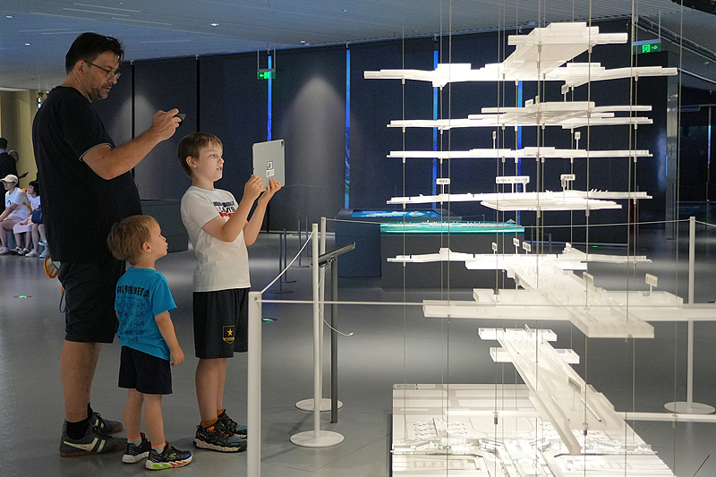 Turistas extranjeros observan una maqueta de planificación y construcción urbana en el Centro de Exposiciones de Planificación Urbana de Shanghai el 10 de agosto de 2025. Foto: VCG