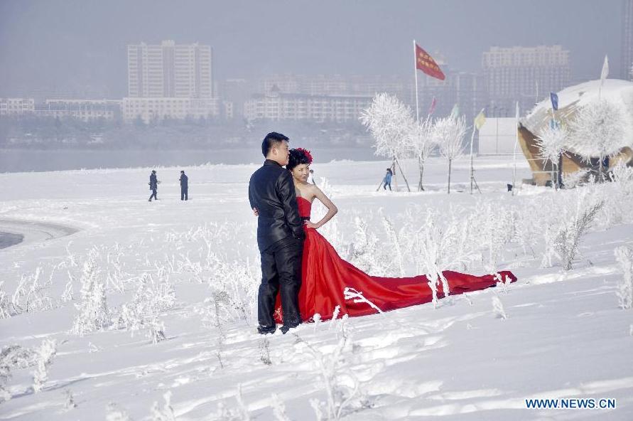 Pareja recién casada disfruta de escarcha a lo largo del río Songhua en Jilin