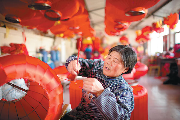 Yan Wanqin, de 64 años, añade pegamento a una pieza de seda en Hongmiao, en el distrito de Huairou, en Pekín, el 26 de enero. Es la trabajadora más antigua del taller de linternas de la aldea. Fotos de Kuang Linhua / China Daily