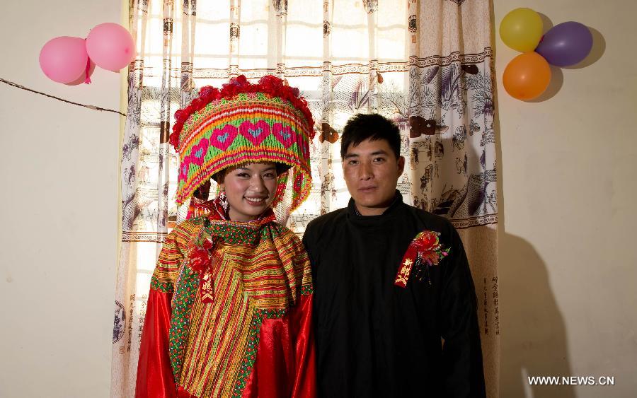 Ji Junxiang (derecha) y Zhang Lu, una pareja de recién casados por el rito de la etnia Lisu, posan ante las cámaras en la vivienda conyugal, en Xinyu, condado de Dechang, provincia de Sichuan, el 15 de febrero de 2013. (Xinhua/Jiang Hongjing)