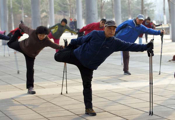 Los participantes realizan estiramientos con la ayuda de bastones en el Parque Forestal Olímpico de Pekín. (Foto: Zou Hong, China Daily)
