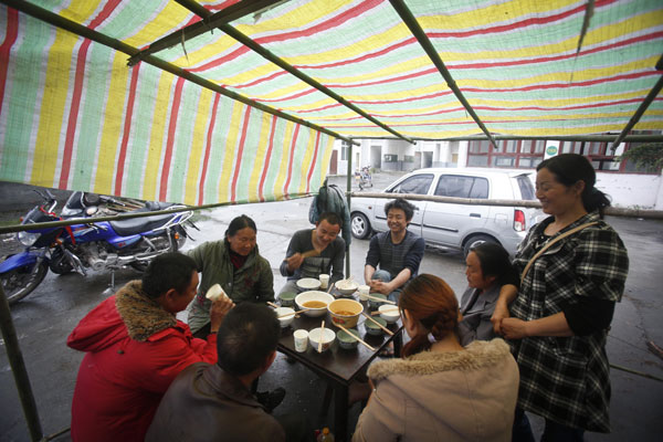 Una familia cena en refugio en la Escuela Media de Lushan, el 23 de abril del 2013. (Foto: Chen Zhuo, Asianewsphoto)