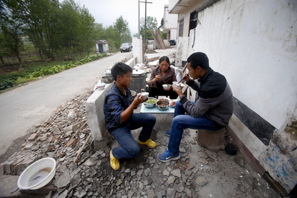 Una familia cena junto a su casa dañada en el pueblo de Qinglongchang, condado de Lushan, el 22 de abril del 2013. (Foto: Chen Zhuo, Asianewsphoto)