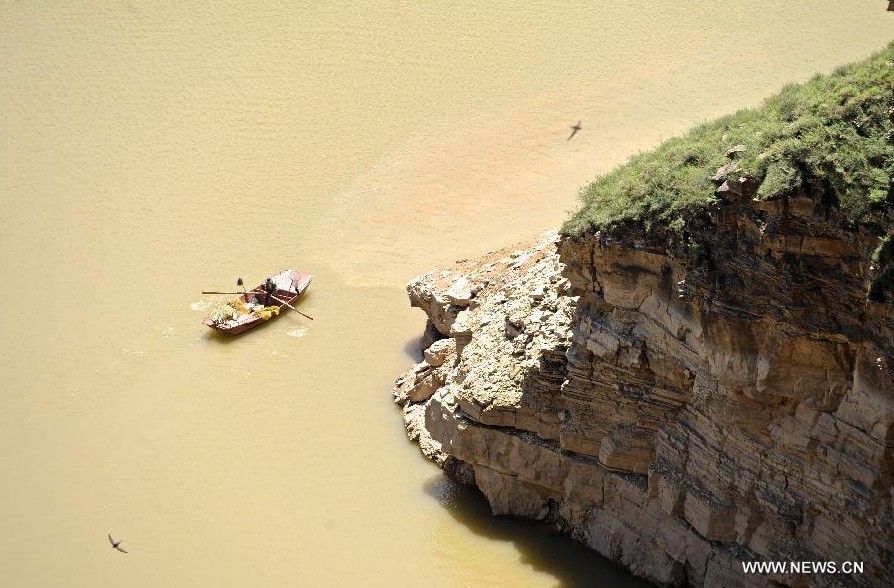 Un aldeano rema en el río Amarillo en Laoniuwan en Hohhot, Región Autónoma de Mongolia Interior, norte de China, el 16 de julio de 2013. La Gran Muralla se encuentra con el río Amarillo en Laoniuwan, que se convirtió en un parque geológico en diciembre de 2012 y se abrió al público el 16 de julio de 2013. (Xinhua / Jin Yu)