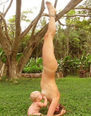 Madre desnuda que amamanta a bebé mientras hace yoga