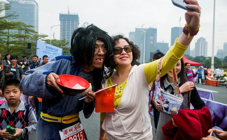 Un“mendigo”se hace una foto con una fan en la Maratón Internacional de Shenzhen, provincia de Guangdong, el domingo. Más de 10.000 personas de 30 países participaron en la carrera. 