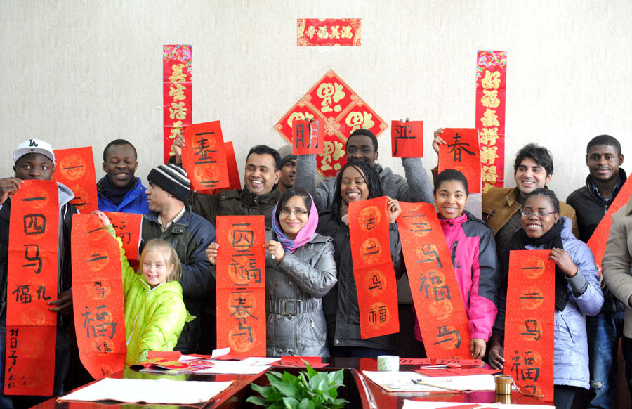 Estudiantes internacionales posan con sus poemas típicos de Año Nuevo Chino en Nanjing, provincia de Jiangsu, el 20 de enero de 2014. [Foto / Asianewsphoto]