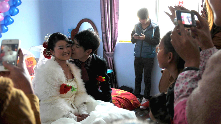 Yuan Bo besa a su esposa Jiang Meiyun rodeado de sus familiares en la aldea de Liantang, Hezhou, en la provincia de Guangxi, el 23 de enero. Una boda en el día de “xiaonian” da buena suerte al matrimonio y sus familias. La pareja se conoció cuando trabajaban en la provincia de Guangdong. 