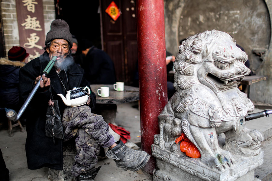 Un hombre fuma una pipa y bebe té en una casa de té del municipio de Linhuan, en Suixi, provincia de Anhui, el 22 de febrero de 2014. [Foto/Asianewsphoto]