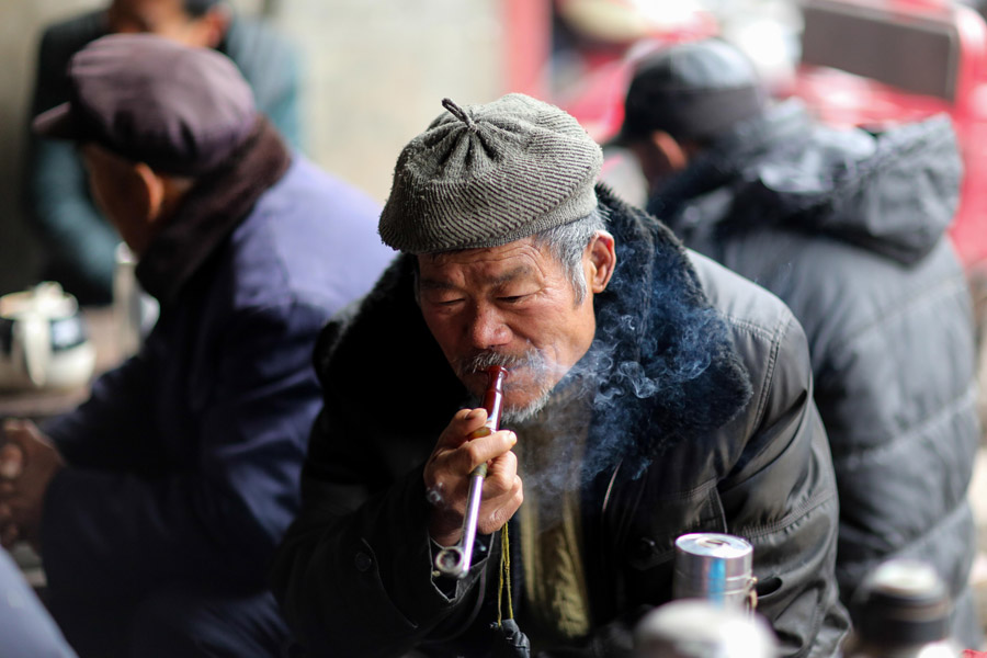 Un hombre fuma una pipa en una casa de té del municipio de Linhuan, en Suixi, provincia de Anhui, el 22 de febrero de 2014. [Foto/Asianewsphoto]