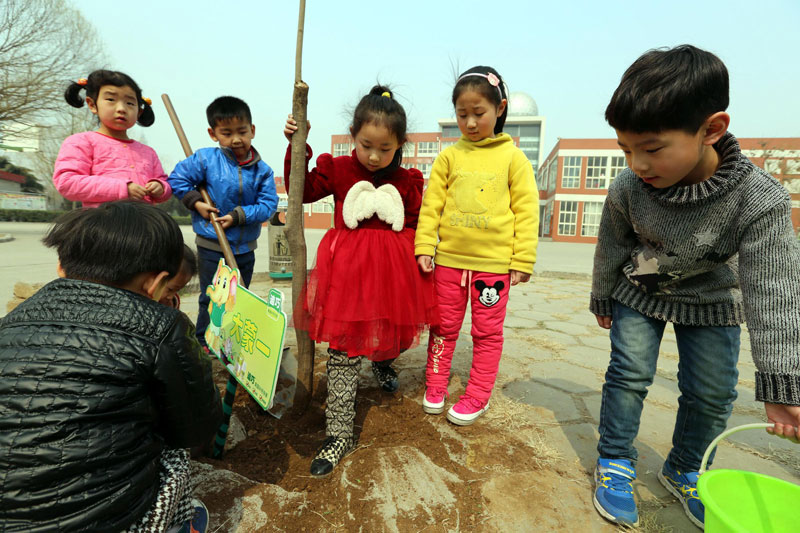 Niños plantan árboles el 10 de marzo en una guardería de la ciudad de Anyang, provincia de Henan, en vísperas del Día de la Plantación de Árboles que promueve una mayor responsabilidad ambiental y un estilo de vida con bajas emisiones de carbono. [Foto/Xinhua]