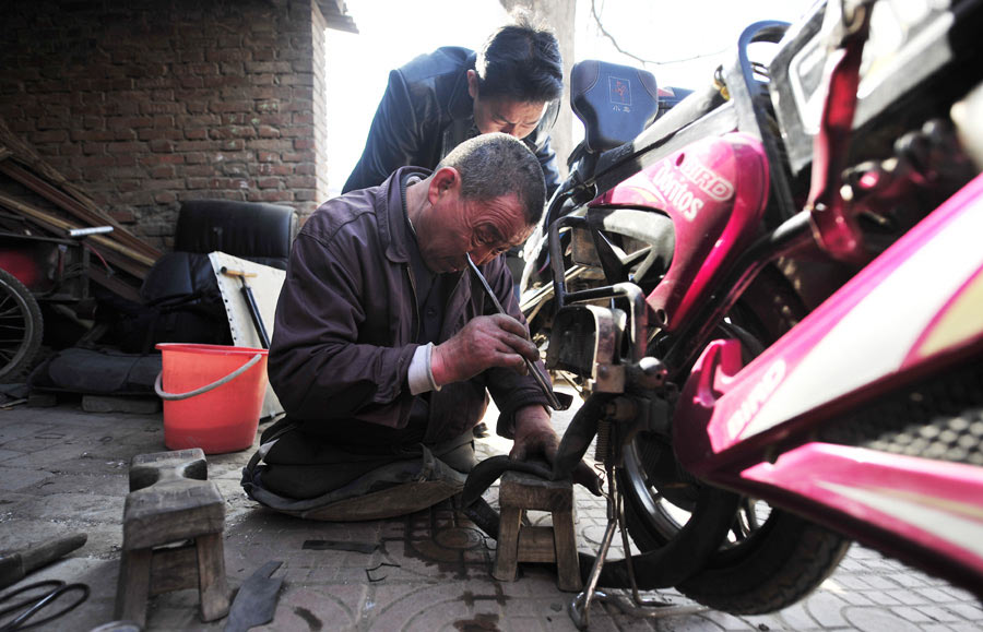 Lu Jianxin, quien perdió ambas extremidades en un incendio hace 30 años, arregla una silla de ruedas en Luoyang, provincia de Henan, el 16 de marzo, en un taller de reparación de bicicletas que ha dirigido desde hace más de dos décadas. [Fotografía por Huang Zhengwei/Asianewsphoto]