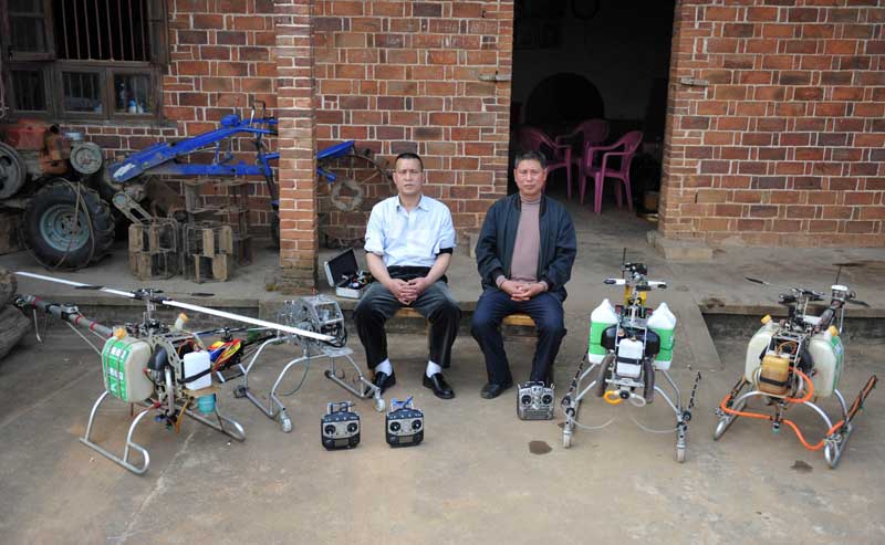 Zhang Aiguo (derecha) y su amigo sentados junto a los drones caseros en Changsha, provincia de Hunan, el 20 de marzo. Zhang espera tener un total de 30 aviones no tripulados antes de 2017 para poder fumigar los campos de arroz del condado. [Foto/Xinhua]