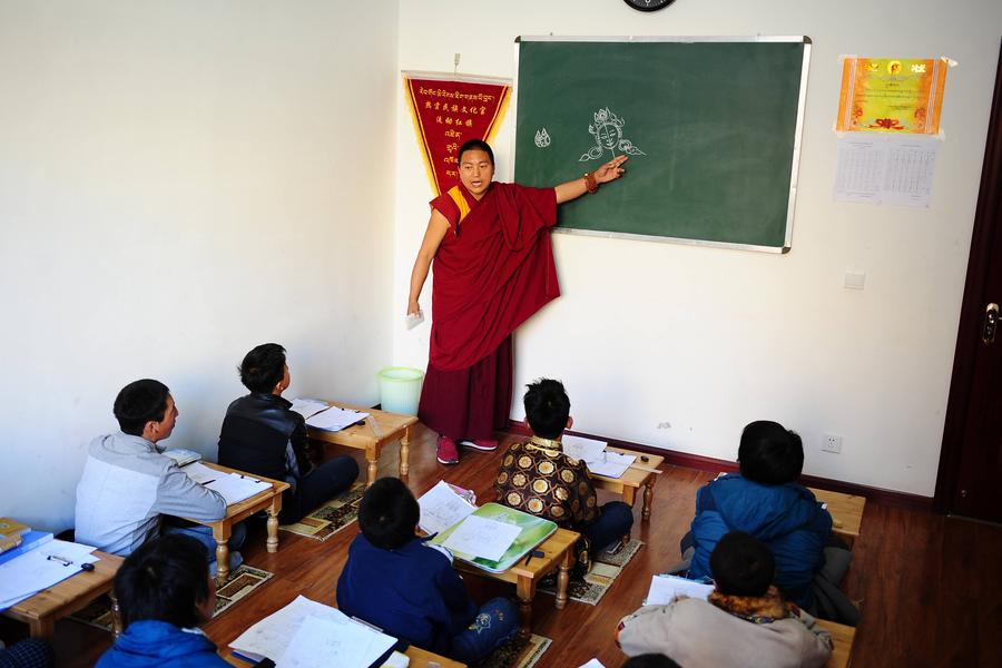 Gazang Jiacuo, un monje tibetano y pintor de Thangka, enseña a los estudiantes las habilidades básicas de la pintura Thangka en su Palacio de la Cultura Étnica de Regong, en la provincia de Qinghai. Foto del 18 de marzo de 2014. [Foto / Xinhua]
