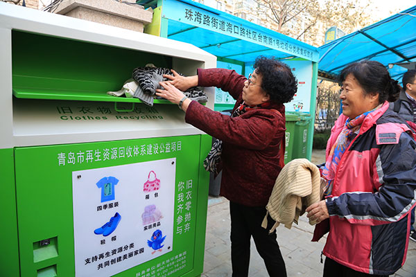 Las personas depositan la ropa usada en un contenedor de reciclaje en el distrito Shinan de Qingdao. [Foto/chinadaily.com.cn]
