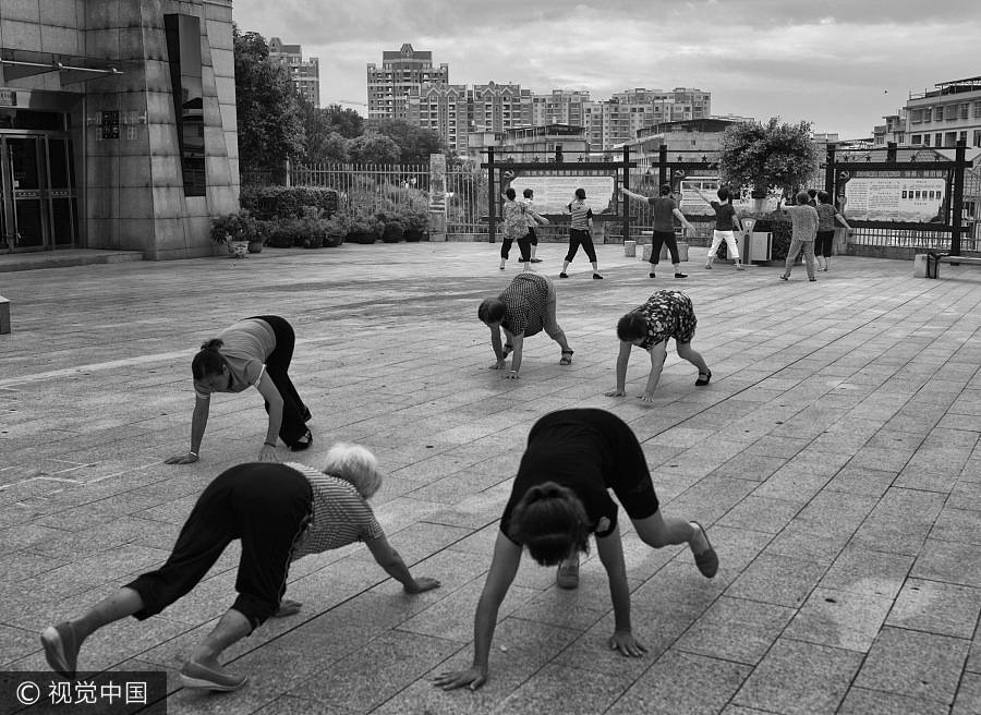 La gente de la provincia de Jiangxi participa en un baile de plaza, en el que algunas mujeres gatean como parte del ejercicio al aire libre, el 13 de agosto de 2016. [Foto / VCG]