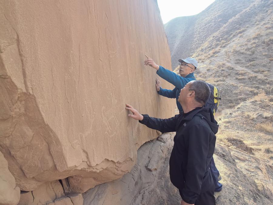Imagen del 13 de marzo de 2025 de investigadores inspeccionando representaciones de una pintura rupestre antigua encontrada en la ladera de una colina en la orilla este del río Amarillo, a unos dos kilómetros de la aldea de Yuwanquan, en el distrito de Pingchuan, en la ciudad de Baiyin, en la provincia de Gansu, en el noroeste de China. (Xinhua/Equipo de investigación de reliquias culturales de Pingchuan) 