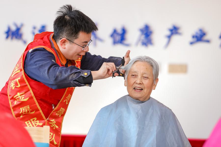 Esta foto de archivo muestra a un voluntario cortándole el pelo a una anciana en un centro de atención a la tercera edad en la ciudad de Qingdao, en la provincia oriental china de Shandong. (Xinhua/Zhang Ying)