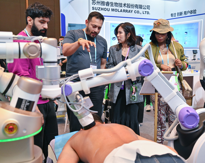 Compradores reciben información sobre un robot para fisioterapia durante la edición 138 de la Feria de Cantón, conocida oficialmente como Feria de Importación y Exportación de China, en Guangzhou, provincia meridional china de Guangdong, el 3 de noviembre de 2025. (Xinhua/Xiao Ennan)